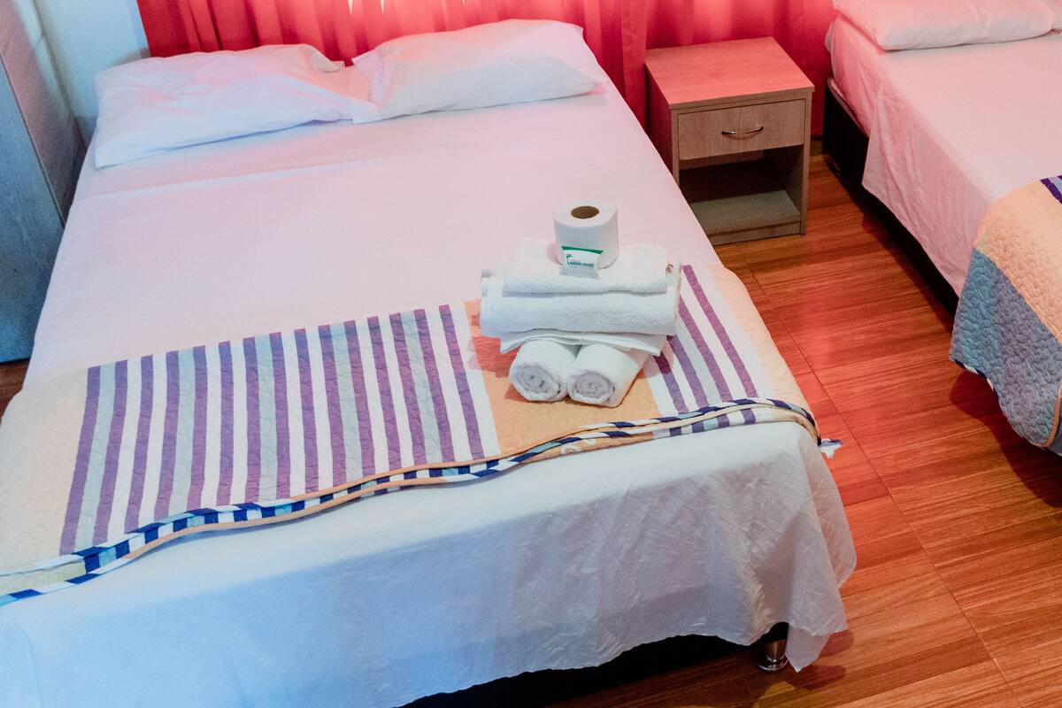 A hotel room with a bed, a nightstand, and a bedside table.