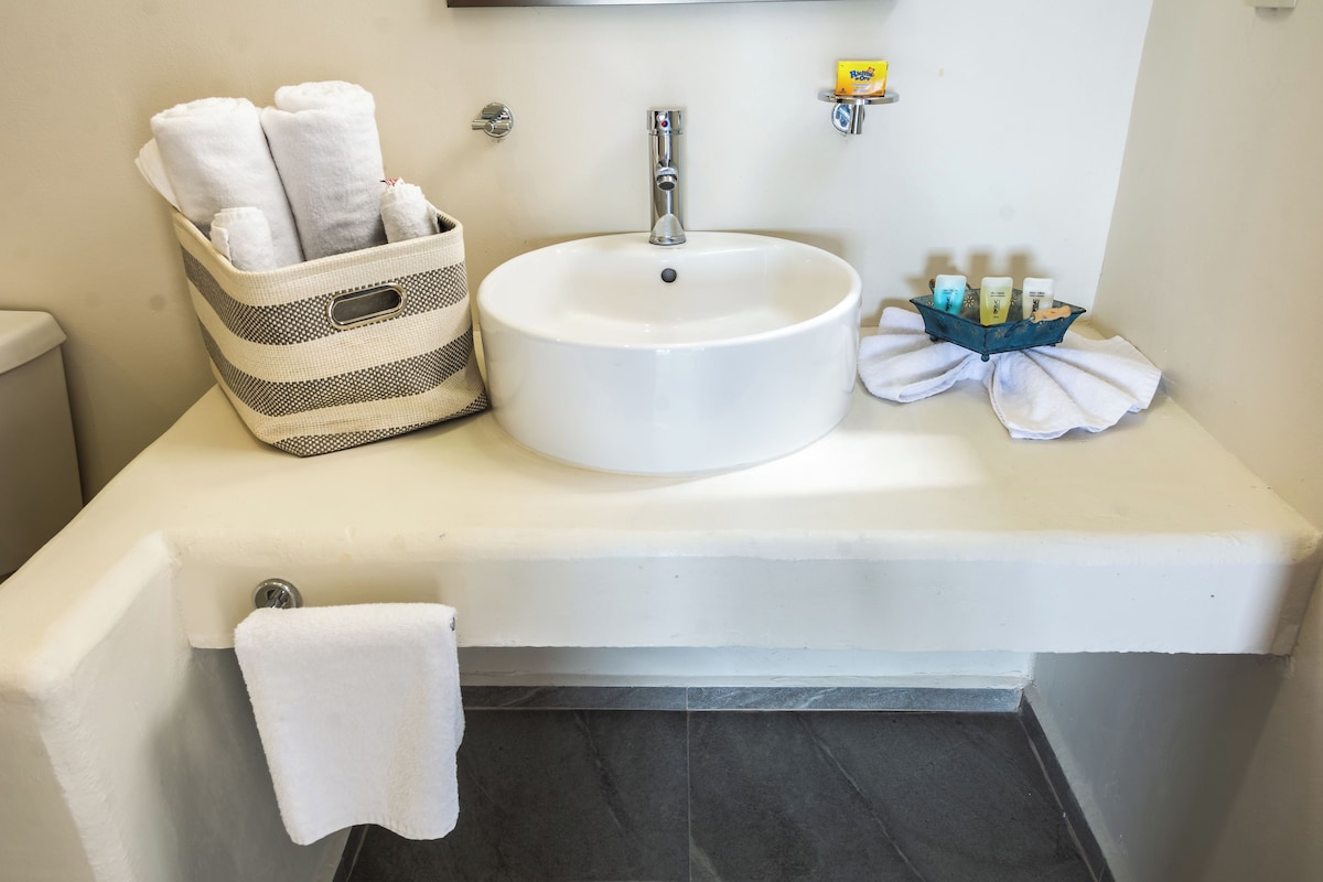 A bathroom with a white sink, a striped towel basket, and a blue container with toiletries.