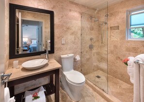 A modern bathroom with a glass-enclosed shower, a large mirror, and a white sink.