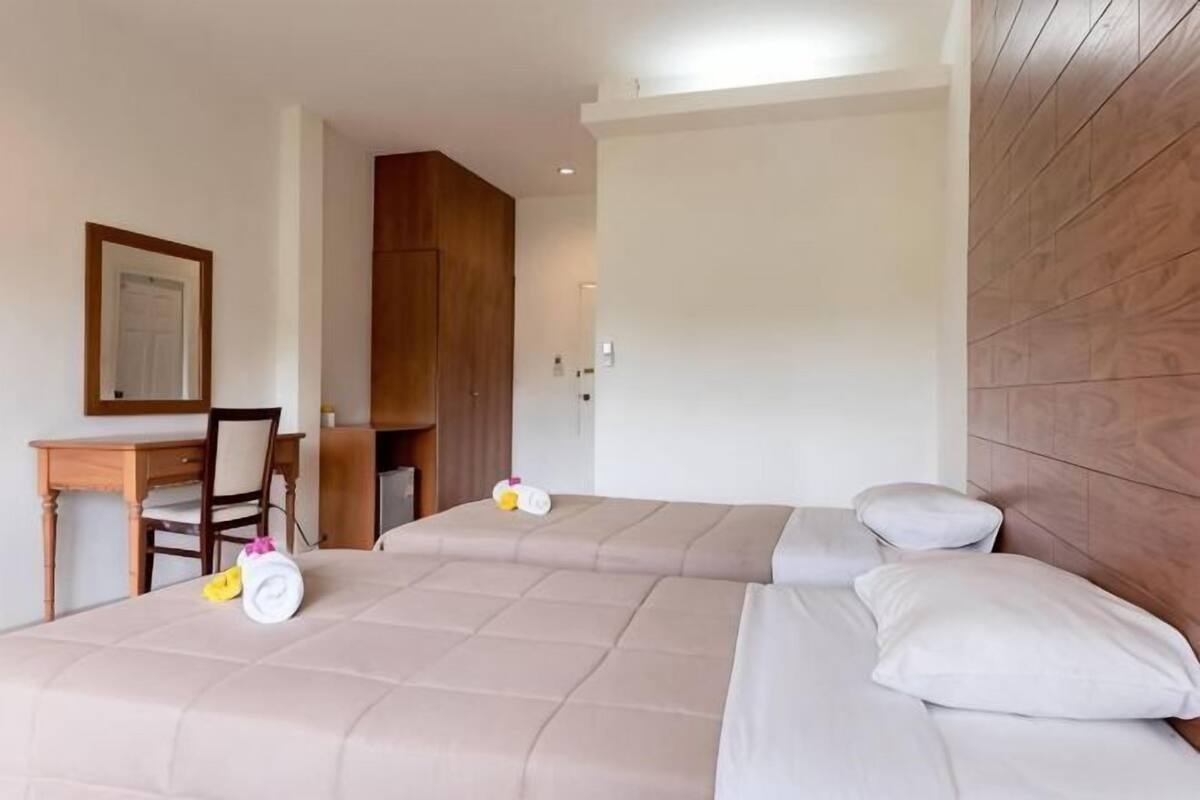 A hotel room with two beds, a desk, and a chair.