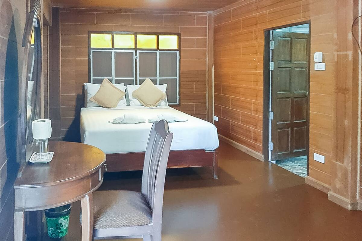 A bedroom with a bed, a chair, a table, and a window.