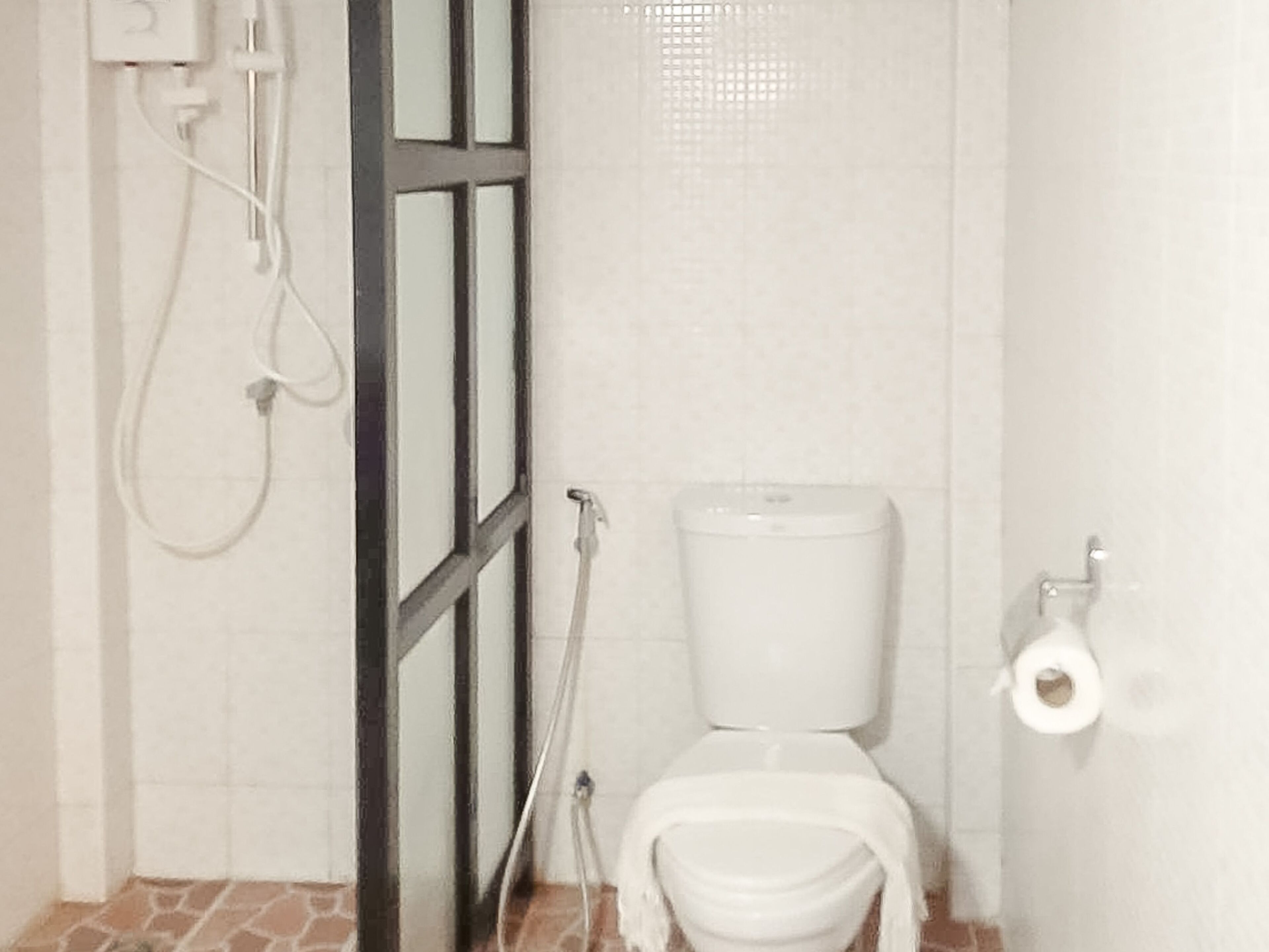 Un baño con inodoro, ducha y toallero.