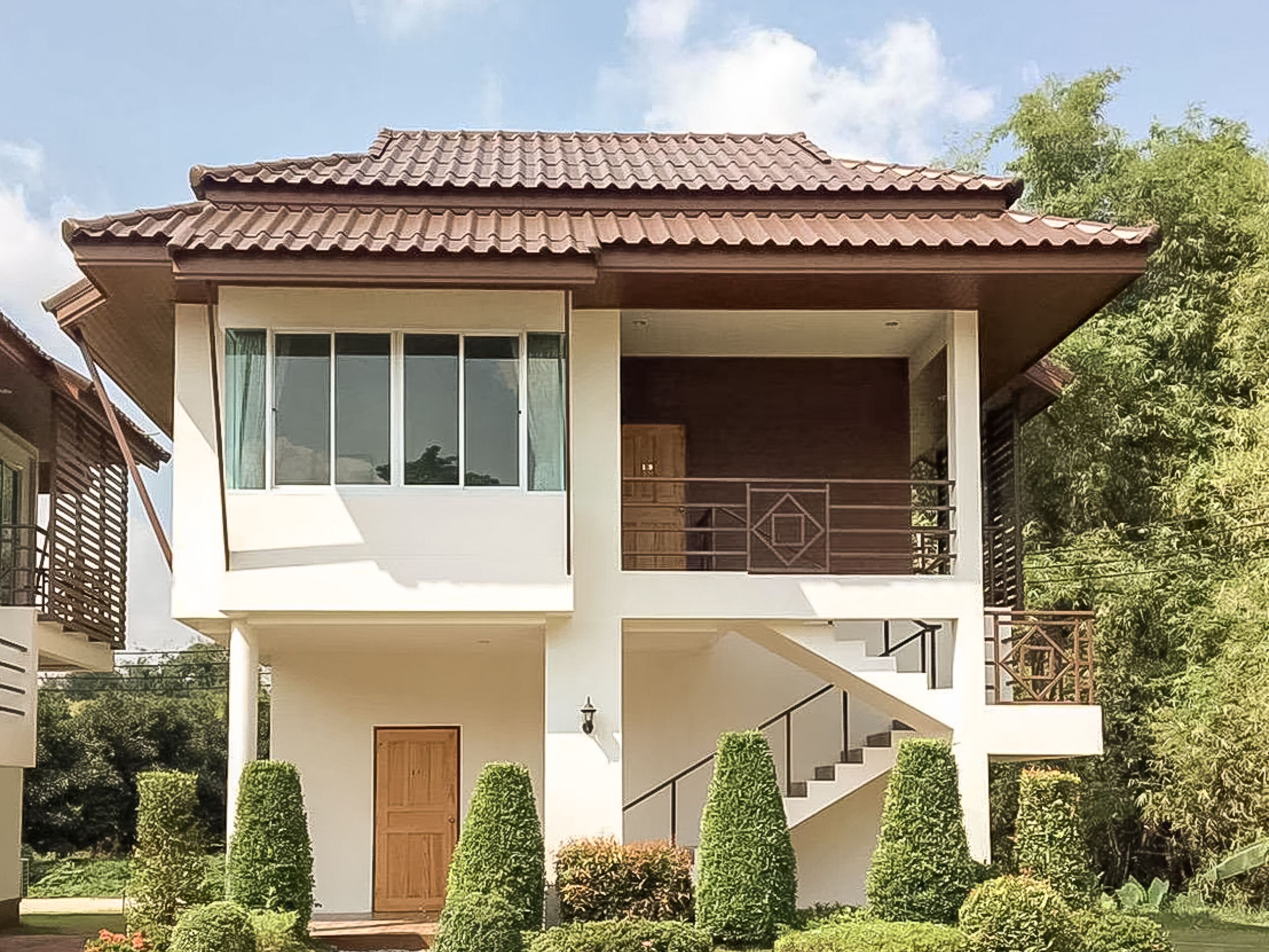 A two-story house with a tiled roof, a staircase, and a front door.
