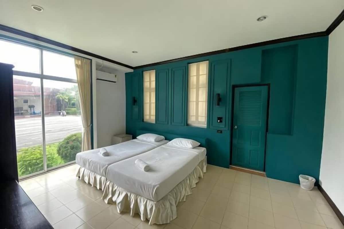A hotel room with two beds, a window, and a door.