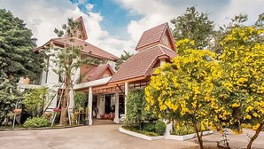 A traditional building with a tiled roof, surrounded by greenery and a clear sky. - Wangyao Riverside Resort (Nakhon Nayok)