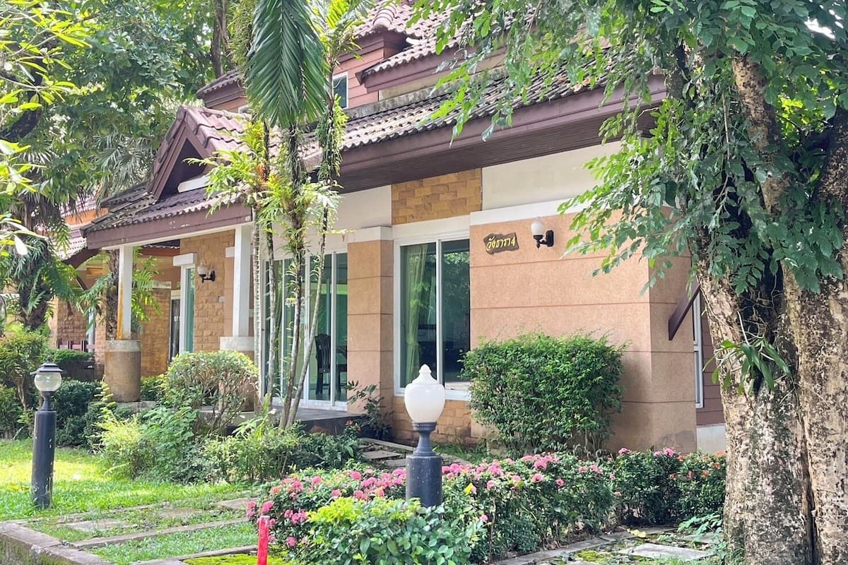 A traditional building with a tiled roof, surrounded by lush greenery and flowering plants.