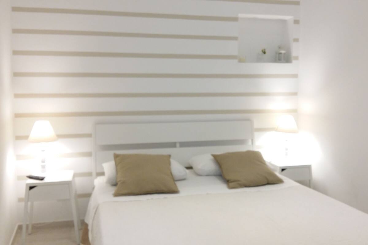 A neatly arranged bedroom with a large bed, two bedside tables, and a nightstand.