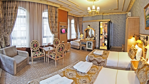 A luxurious hotel room with a sofa, two chairs, a desk, a bed, and a mirror. - Sirkeci Gar Hotel (Istanbul)