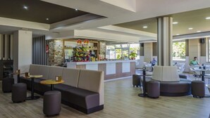 A modern hotel lobby with a central seating area, a bar, and a counter with a variety of items. - Hotel Maracaibo (Sanxenxo)