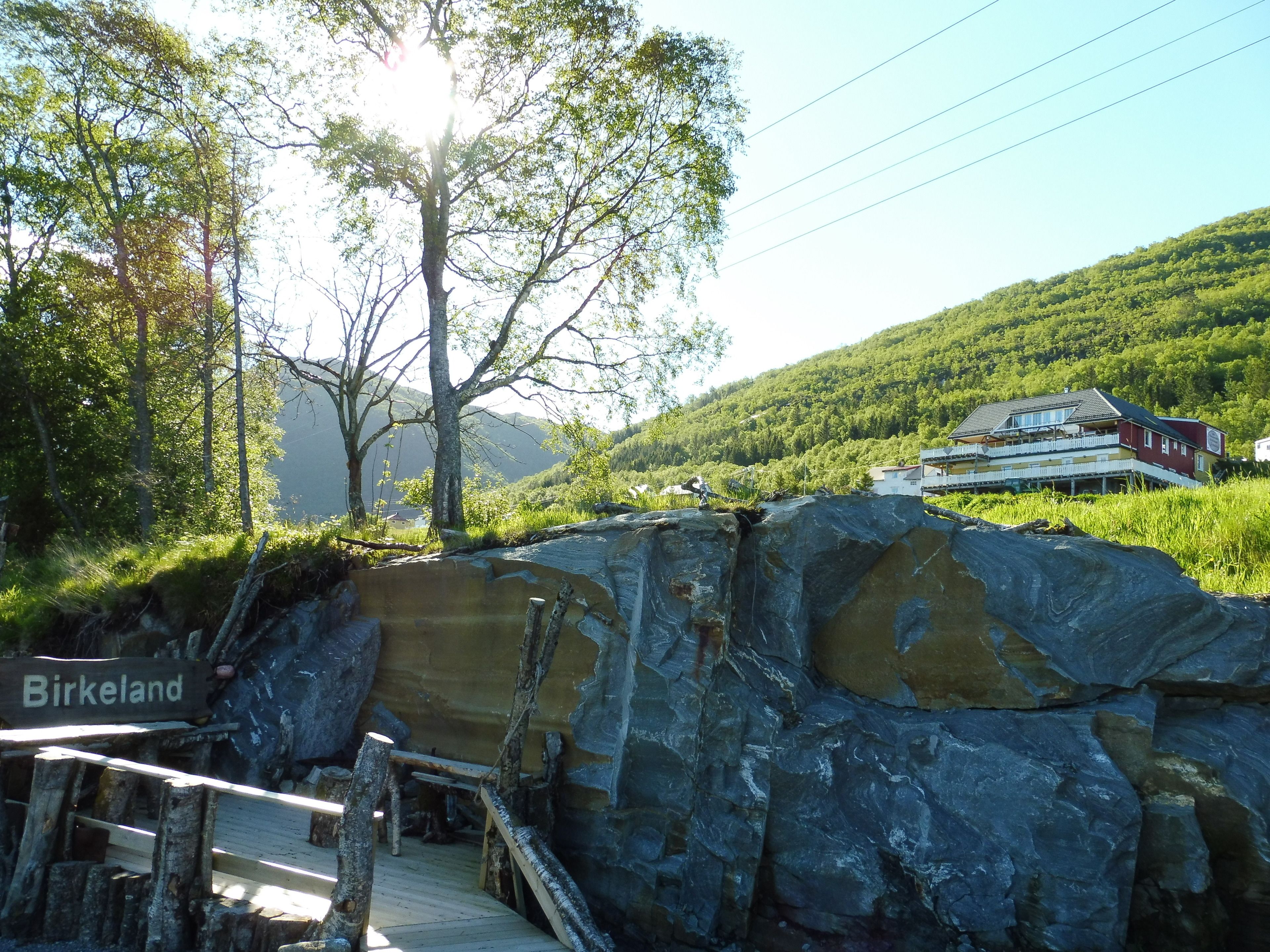 A wooden bridge over a rocky terrain with a sign reading "Birkeland".