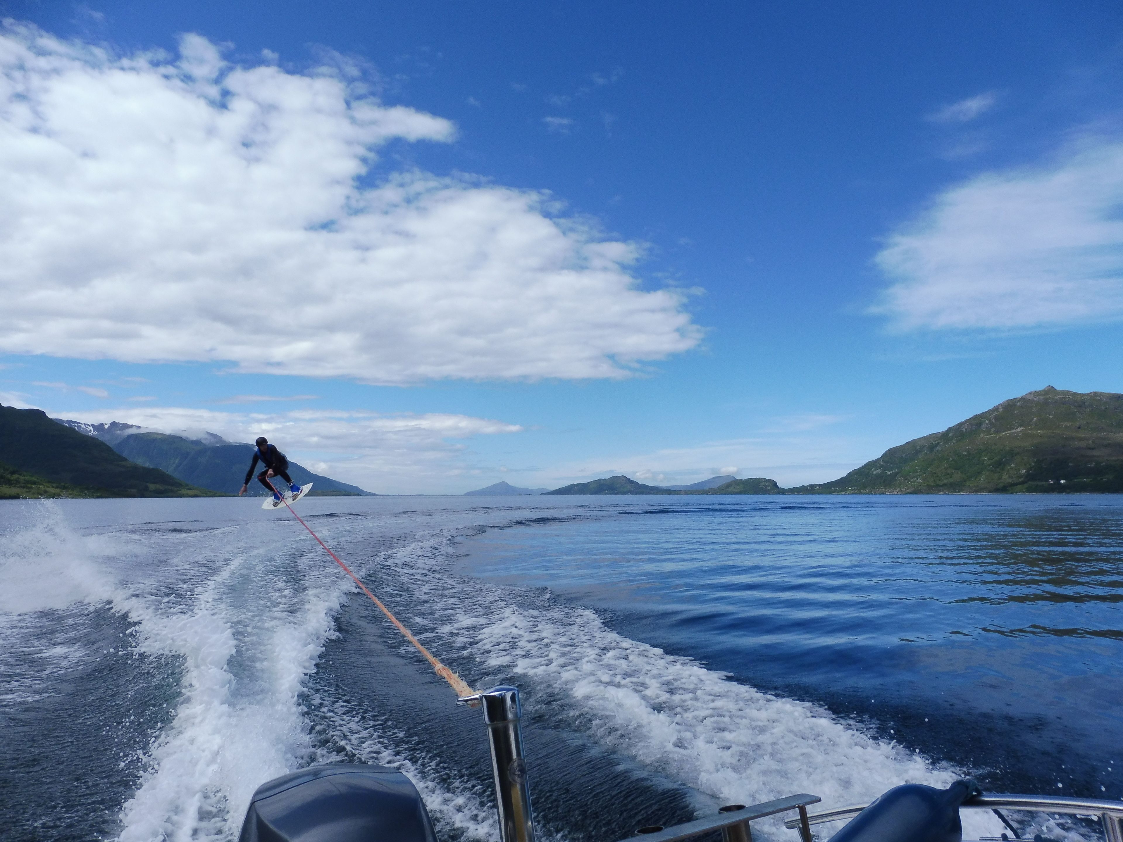 A person wakeboarding on a lake with mountains in the background.