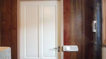 A white door with a handle, set in a wooden wall with a vertical panel design.
