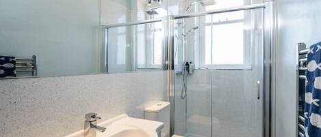 Un baño moderno con lavamanos independiente, inodoro y ducha con cerramiento de vidrio.