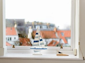 A model sailboat on a windowsill with a view of buildings outside. - Bass Rock View (North Berwick)
