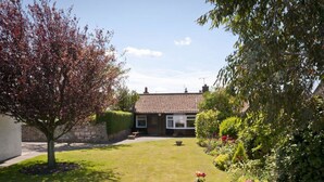 A house with a tiled roof, a front lawn, and a stone wall in the foreground. - Greylag Cottage (Gullane)