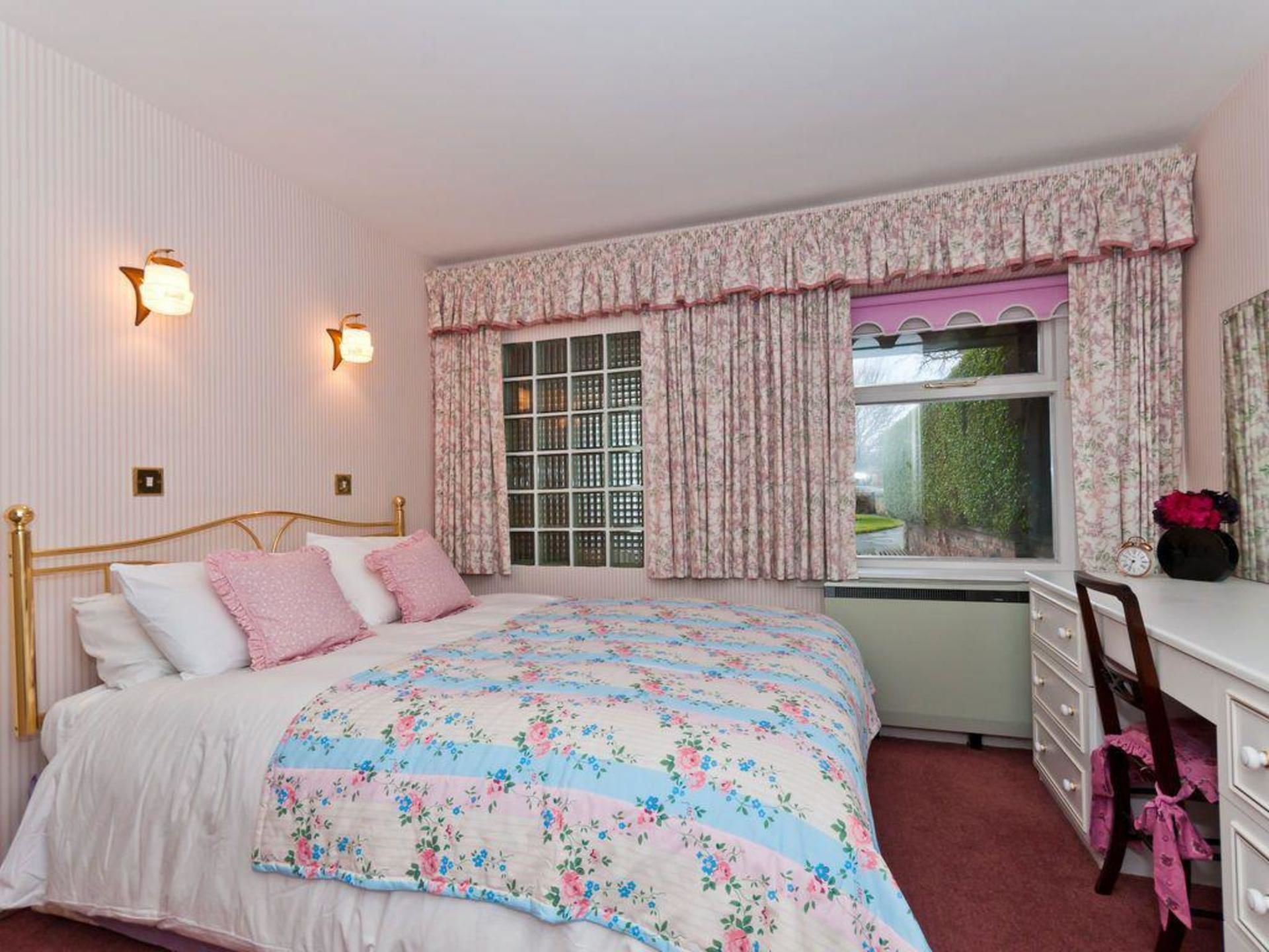 A bedroom with a bed, a dresser, a chair, and a window with curtains.