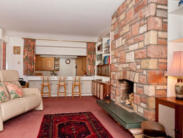 A cozy living room with a fireplace, a sofa, a coffee table, and a rug.