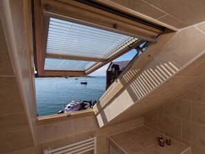 A room with a skylight overlooking a body of water, a tiled floor, and a small window.