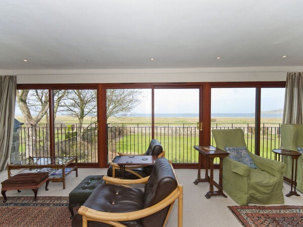 Un balcon spacieux offrant une vue sur la mer, aménagé avec un canapé, des fauteuils et une petite table.
