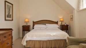 A bedroom with a large bed, two bedside tables with lamps, a dresser, and a chair. - West Links View (North Berwick)