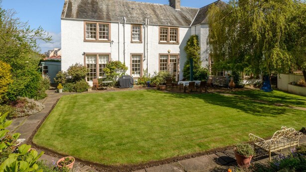 A white two-story house with a well-maintained lawn and garden. - Nungate (North Berwick)