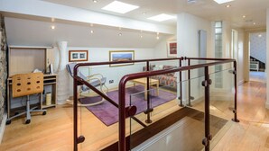 A spacious room with a wooden desk, a comfortable chair, a purple rug, and a glass railing leading to a balcony. - Nungate (North Berwick)