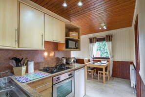 A kitchen with wooden cabinets, a gas stove, a microwave, and a dining area with a table and chairs.