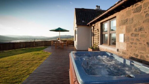 A stone building with a hot tub and a wooden deck. - Rowan Tree Cottage (Cupar)