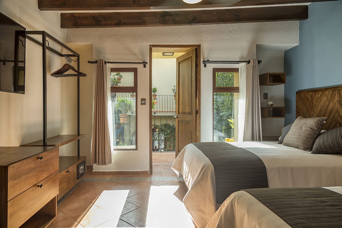 A bedroom with a large bed, a wooden dresser, and a view of the outdoors through a door.