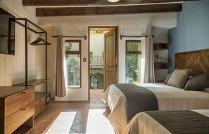 Ein Schlafzimmer mit einem großen Bett, einer Holzkommode und Blick ins Freie durch eine Tür.