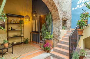 An interior courtyard with a staircase, potted plants, and a bookshelf. - Morazul Hotel Boutique (Querétaro)