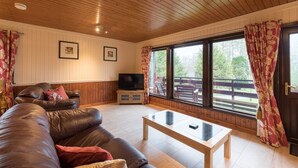 A cozy living room with a leather sofa, a coffee table, and a television. - Bluebell Lodge 2 with Hot Tub (Newton Stewart)