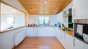Eine moderne Küche mit Holzbalkendecke, weißen Schränken und einer zentralen Kochinsel.