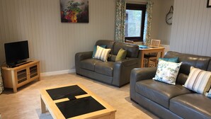 A living room with two sofas, a coffee table, a TV stand, and a window with curtains.