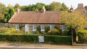 A stone house with a tiled roof, a white picket fence, and a well-maintained garden. - Swifts Cottage (Tranent)