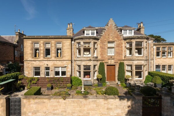 A large, historic stone building with multiple stories, featuring a prominent central tower and symmetrical windows.
