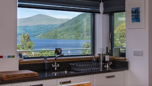 A kitchen with a large window overlooking a lake and mountains.