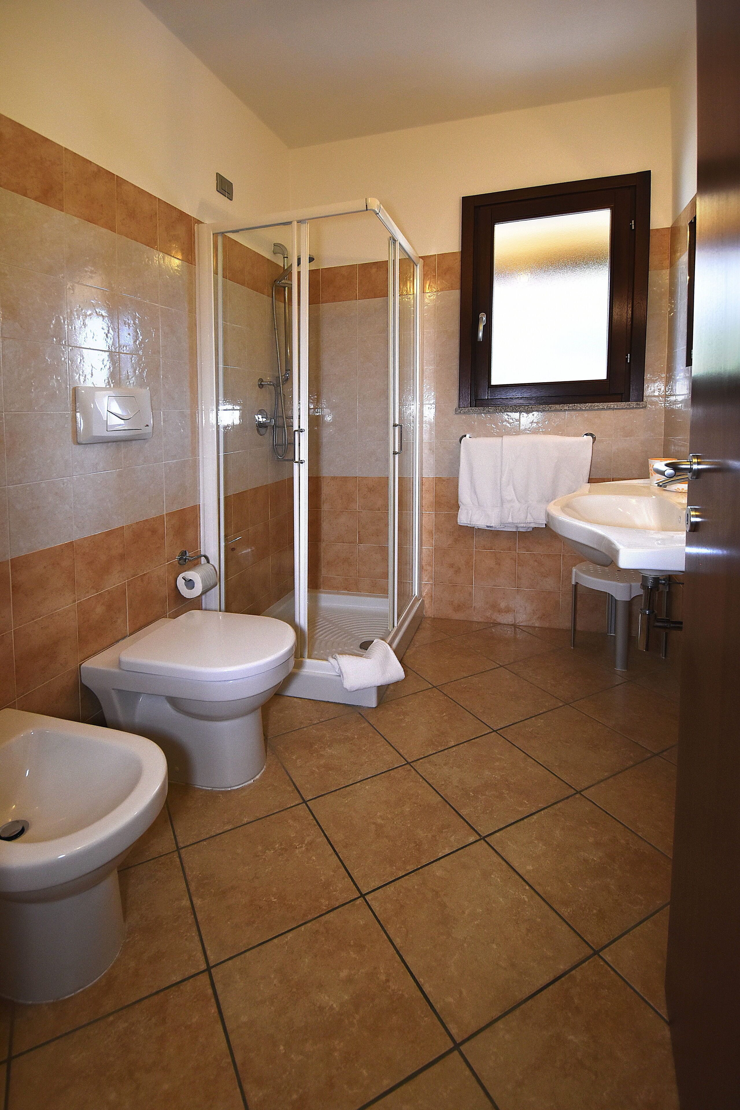 Un baño con ducha, inodoro, bidé y lavamanos.