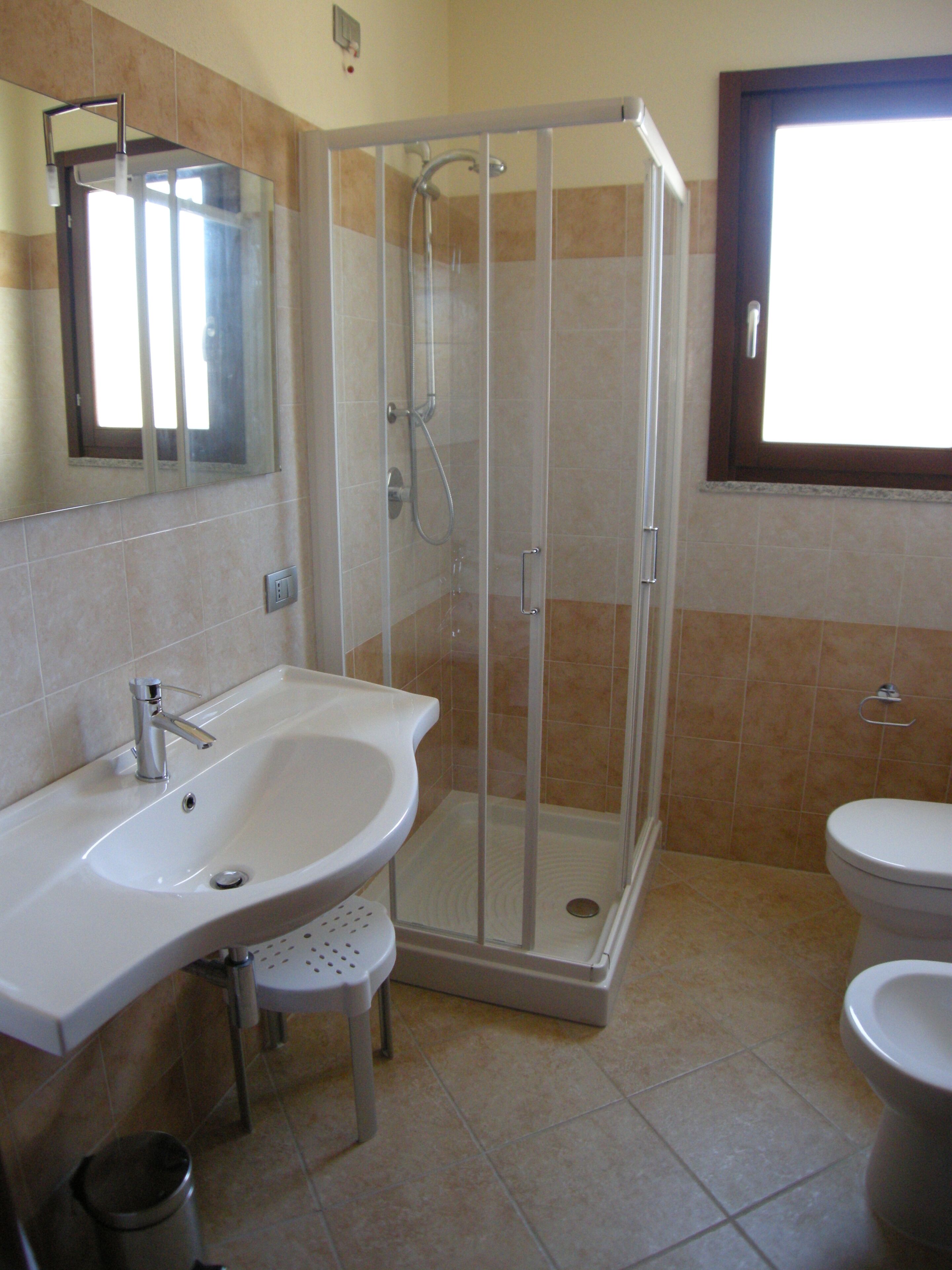 A bathroom with a glass-enclosed shower, a sink with a mirror, and a toilet.