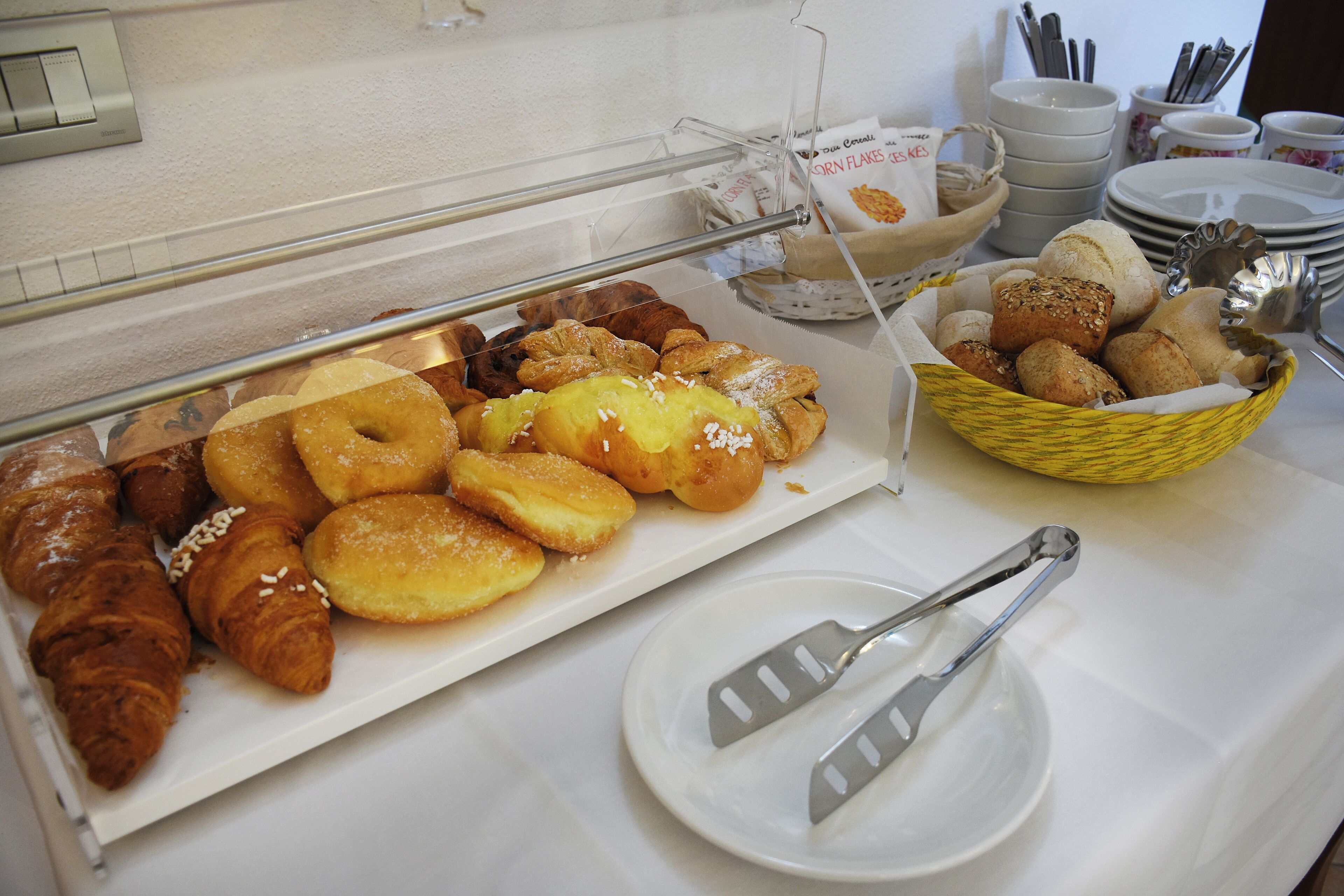 A buffet with various pastries and bread, including croissants and muffins, and a basket of bread rolls.