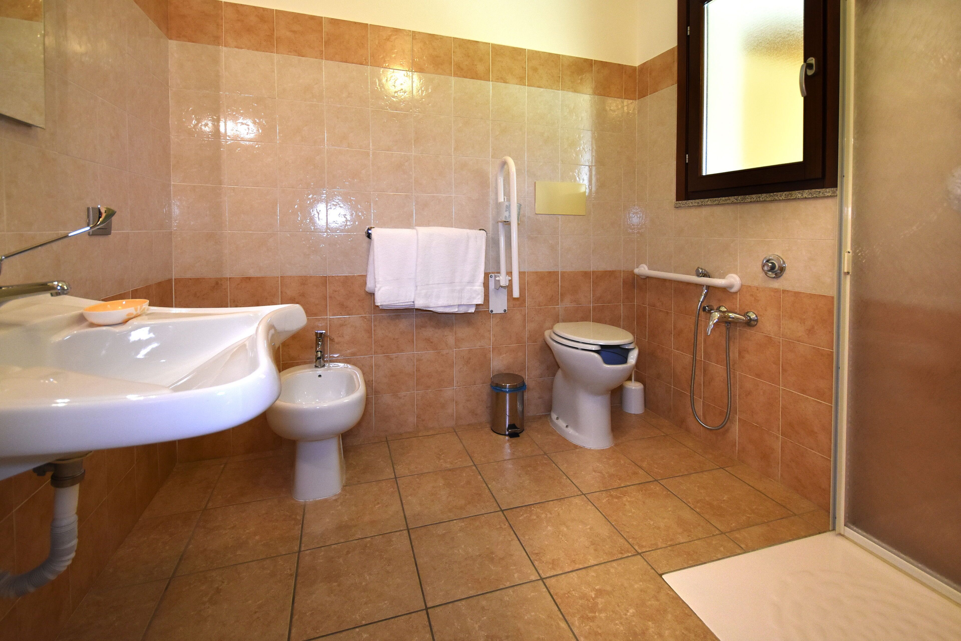 A bathroom with a sink, bidet, toilet, and shower.
