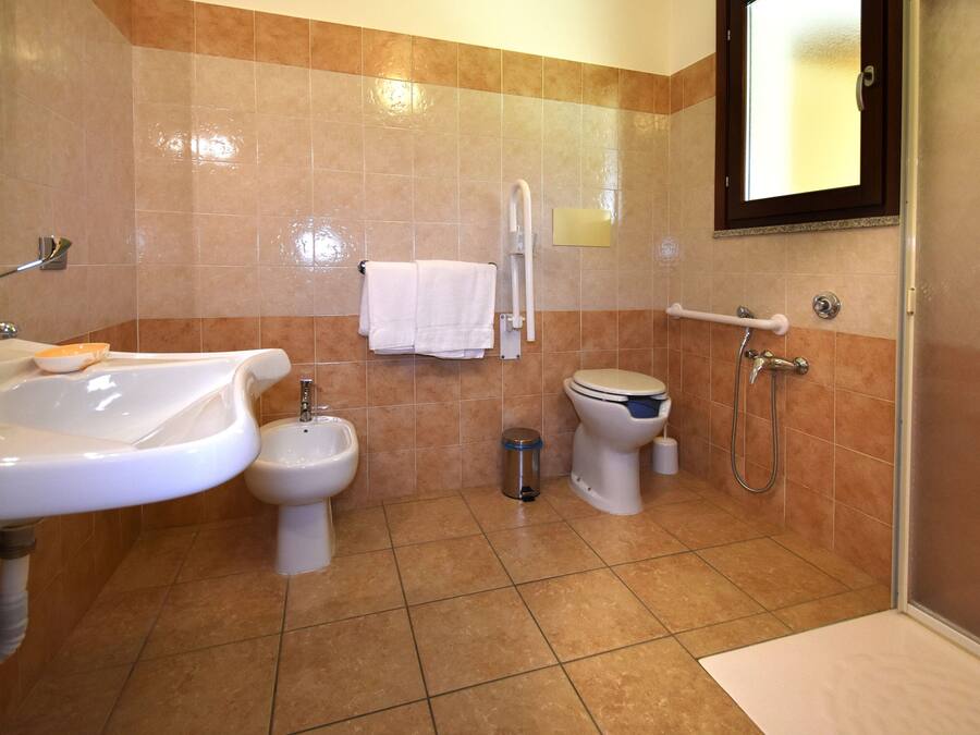 A bathroom with a sink, bidet, toilet, and shower.