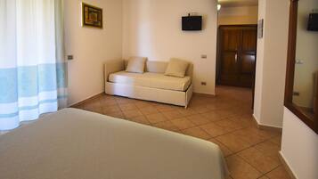 Ein Schlafzimmer mit Bett, einer Schlafcouch, einem Fernseher an der Wand und einer Holztür.