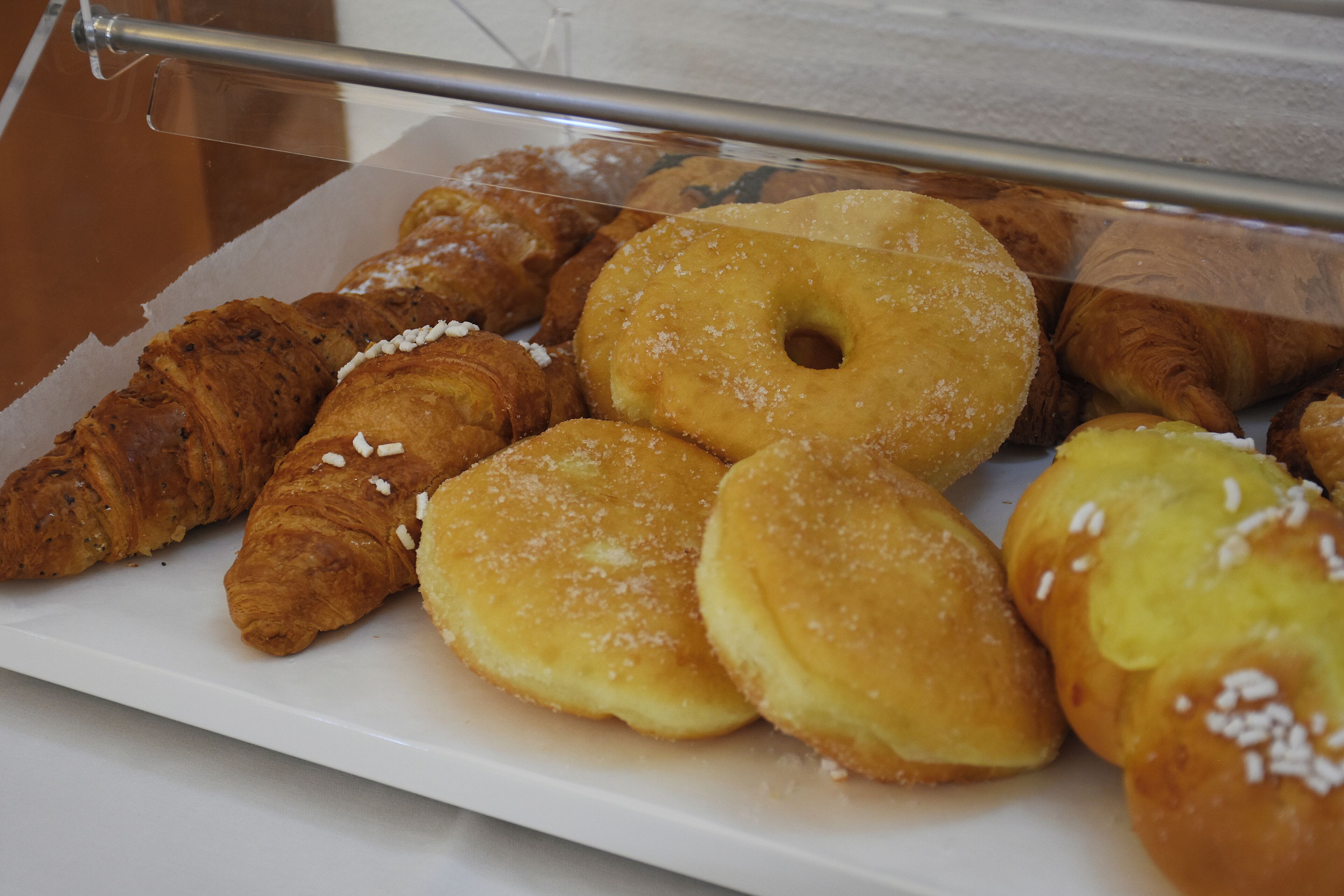 Una vitrina con diversos pasteles, incluyendo croissants y donas.