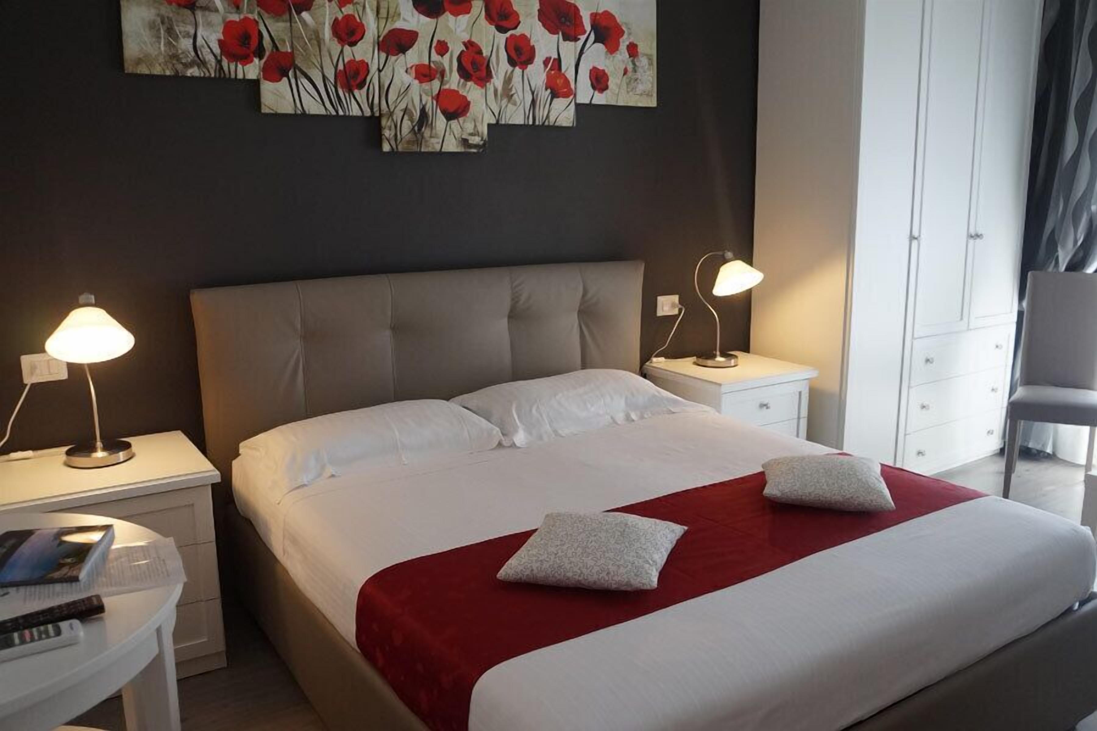 A hotel room with a large bed, two bedside tables, a desk, and a wardrobe.
