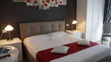 A hotel room with a large bed, two bedside tables, a desk, and a wardrobe.