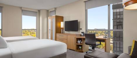 Une chambre d’hôtel avec un lit, un bureau, une chaise et un téléviseur.
