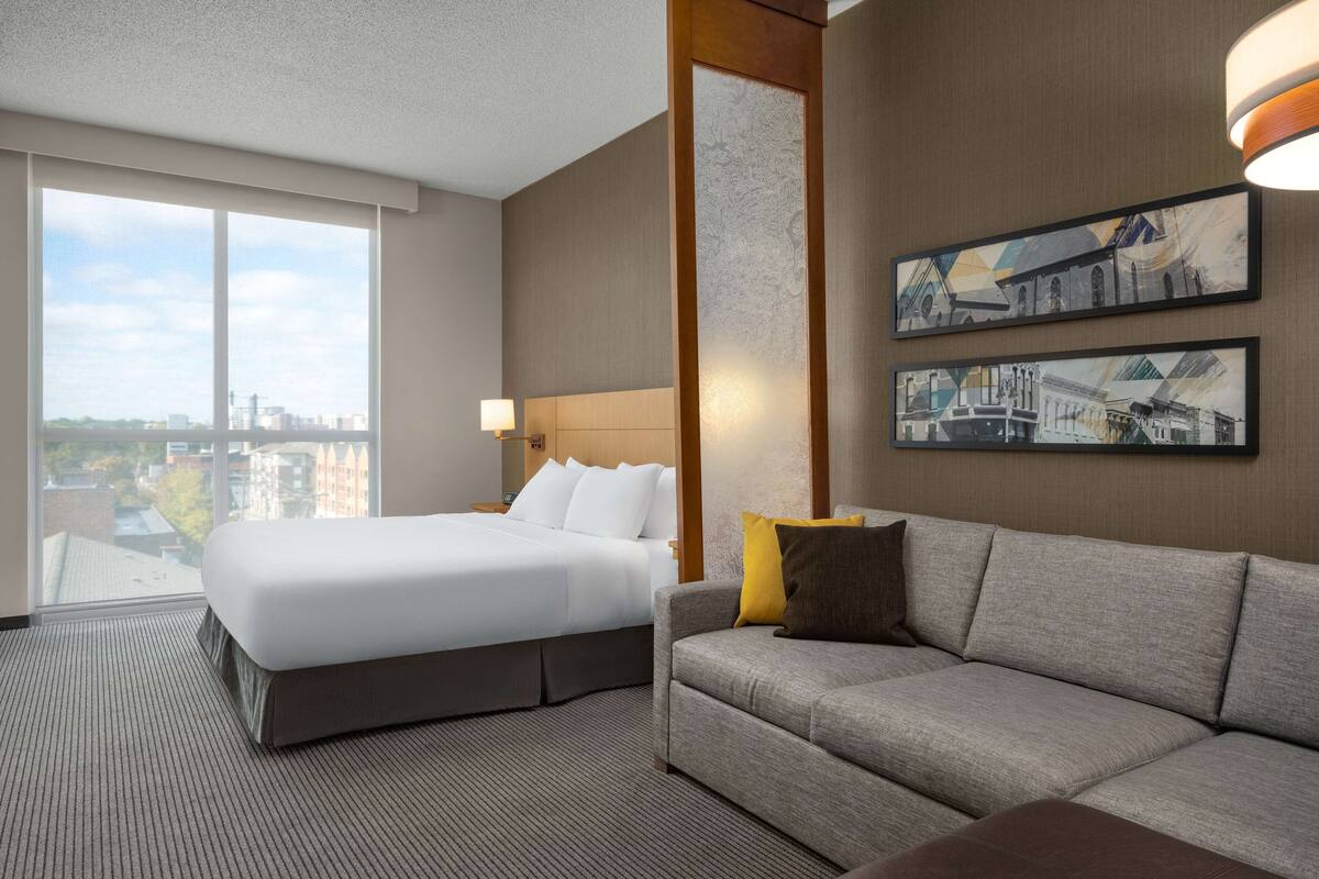 Une chambre d’hôtel avec un grand lit, un canapé et deux tableaux accrochés au mur.