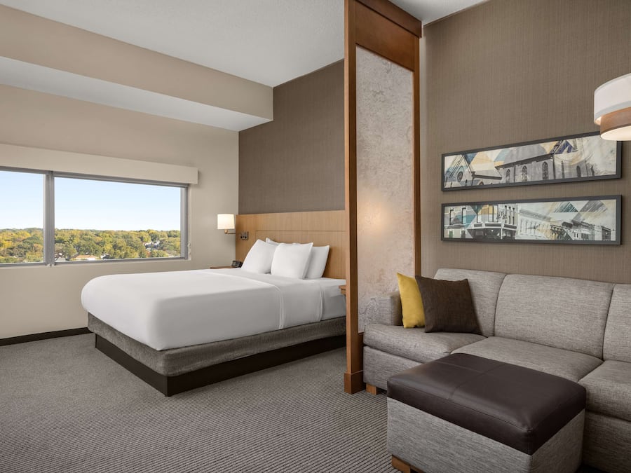 A hotel room with a large bed, a sofa, and two framed pictures on the wall.