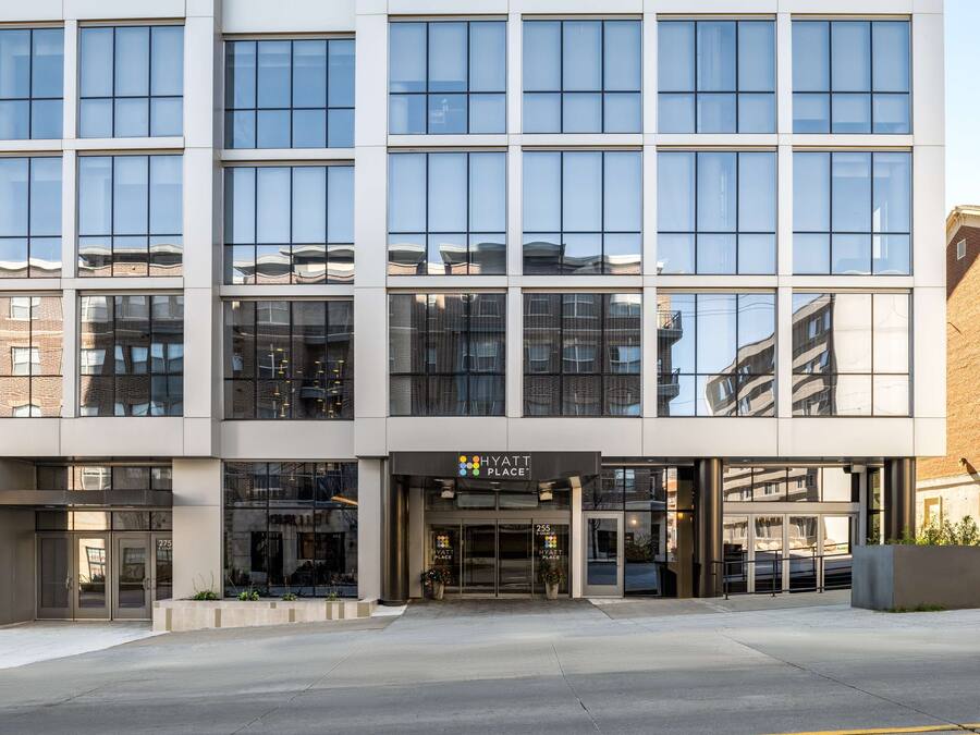 Um hotel moderno Hyatt Place com fachada de vidro, entrada destacada e área de estacionamento.